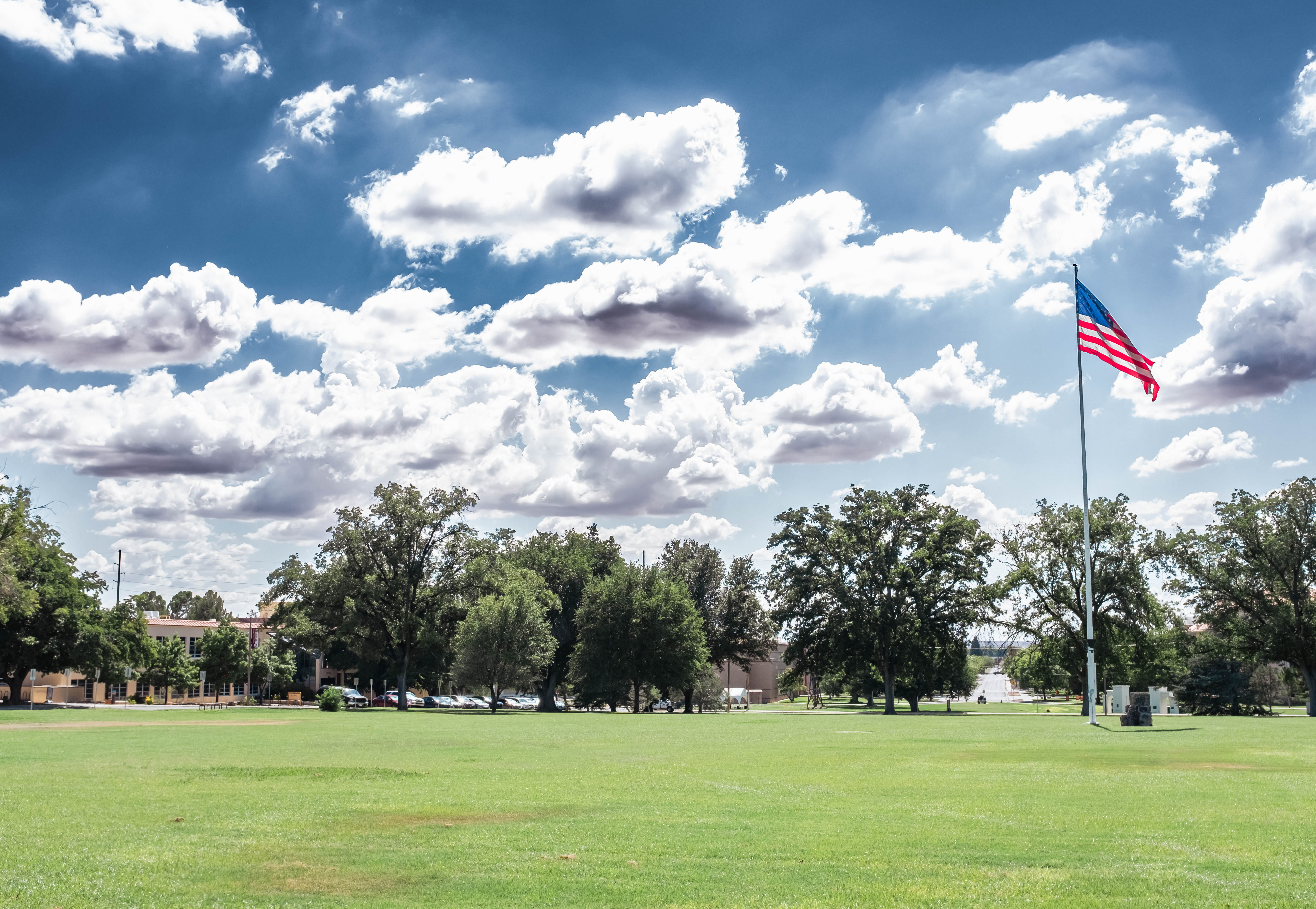 NMSU grass field located at the horseshoe with the American flag at full mast waving in the wind in the right side of the photo. 