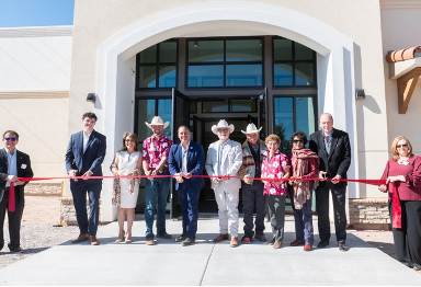 Members of NMSU Leadership and the College of ACES cut a red ribbon in front of the new college buidlings. 
