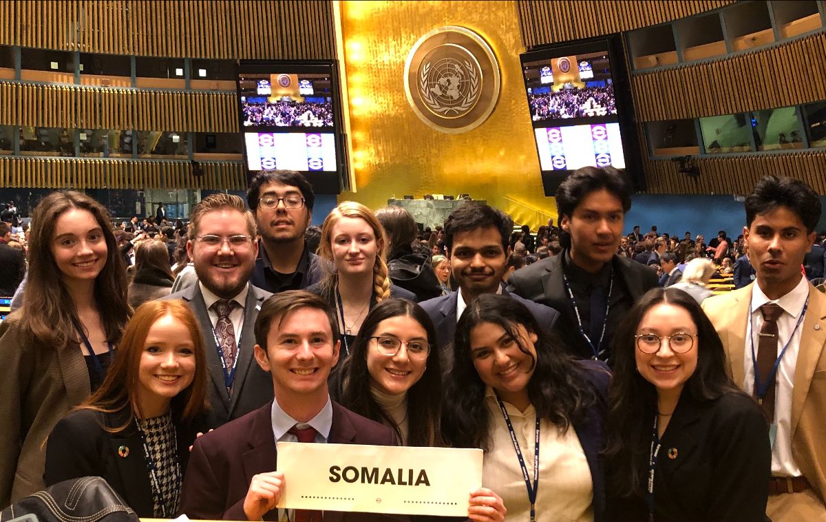 Members of the NMSU Model UN team stand together holding their assigned country sign of Somallia. 