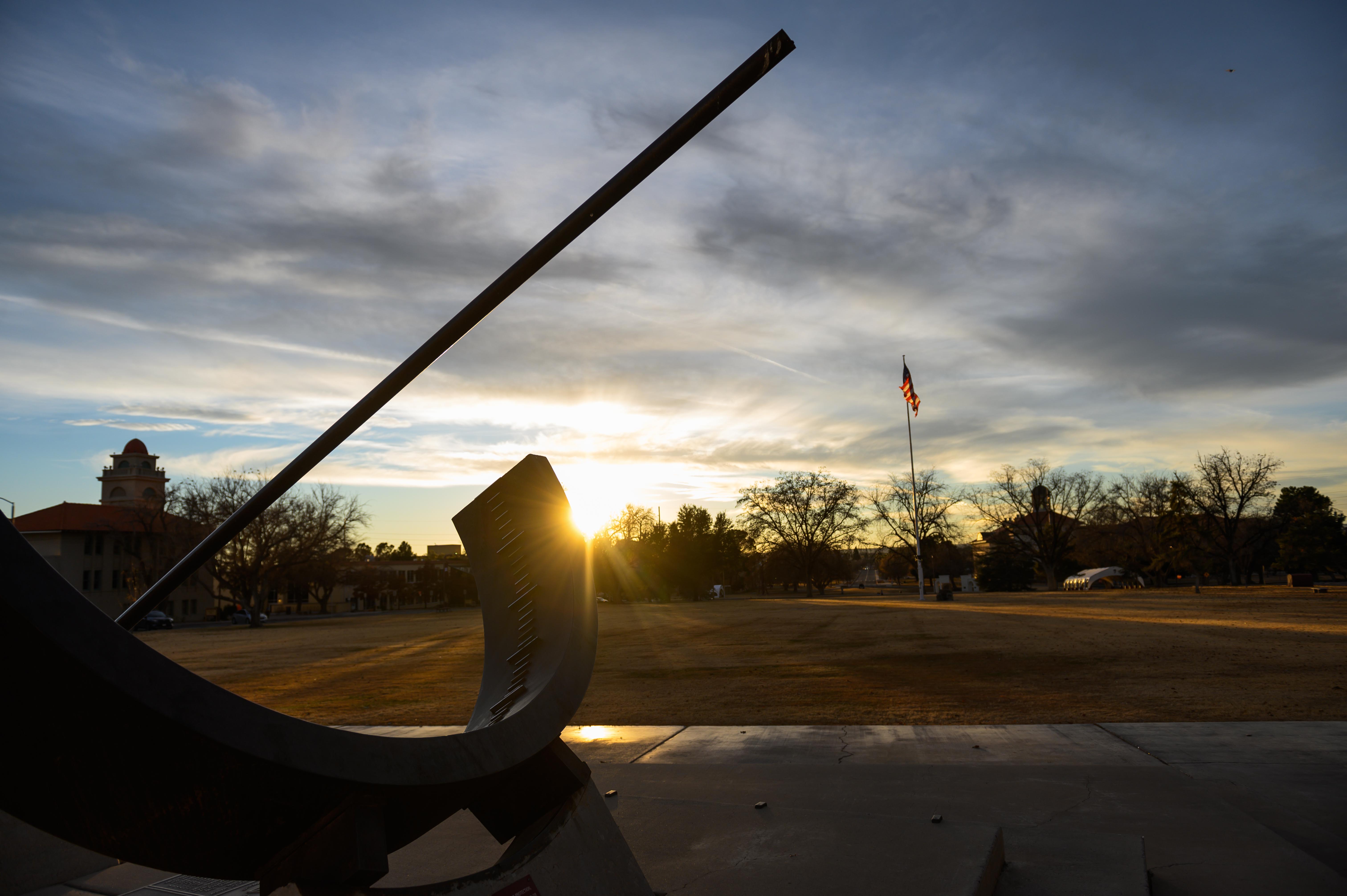 NMSU Campus sun dial on the Horseshoe with the sunsetting behind. 