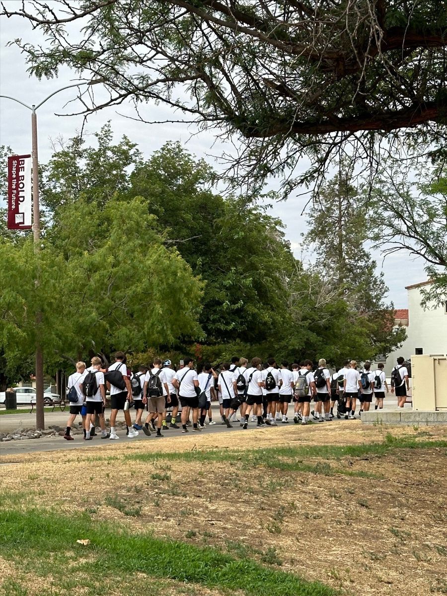 Group of NMSU future students walking to the NMSU Pan American Center in matching white shirts. 