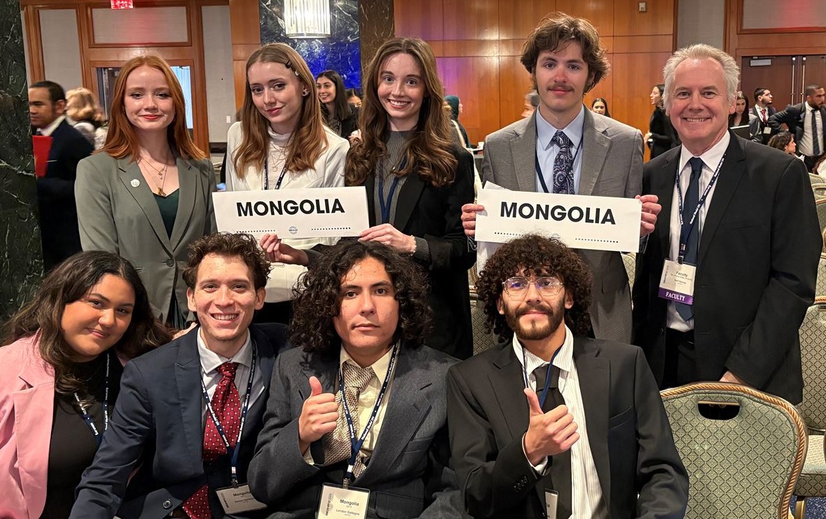 A group of students posing for a photo at a conference, each holding signs with "MONGOLIA" written on them.
